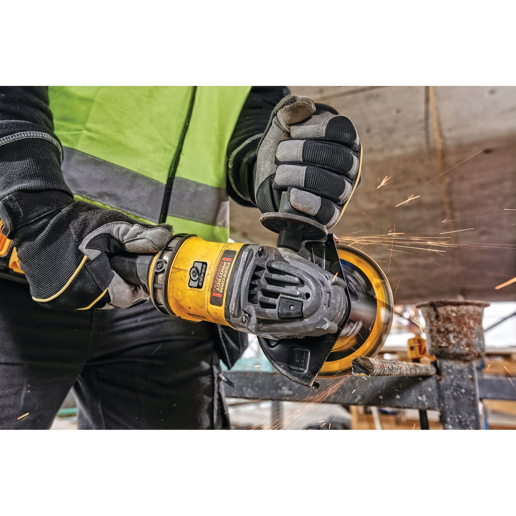 Close-up of a person using a DEWALT angle grinder to cut metal, with protective gloves and a high-visibility vest, sparks flying from the tool.