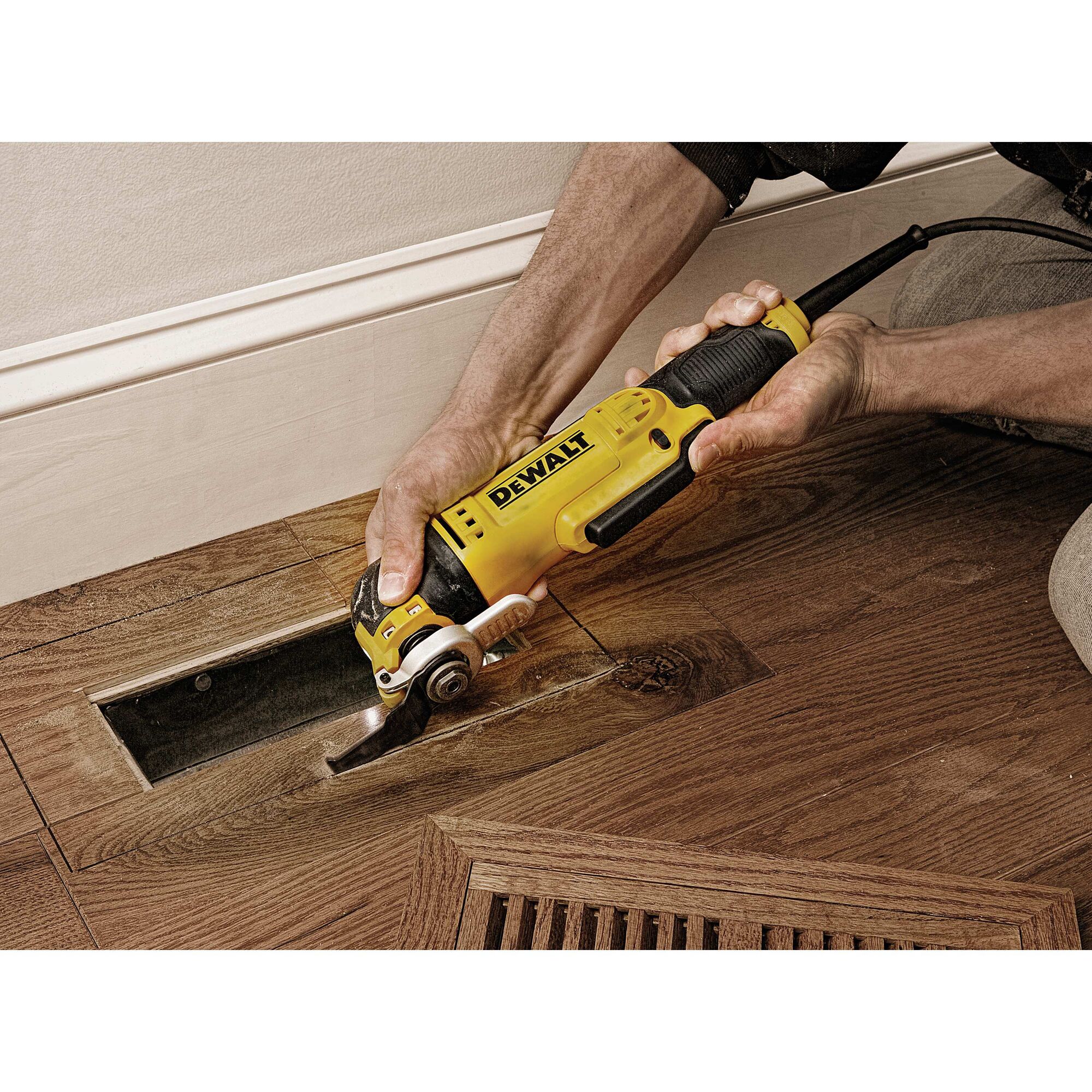 Oscillating multi tool kit being used to cut wood.