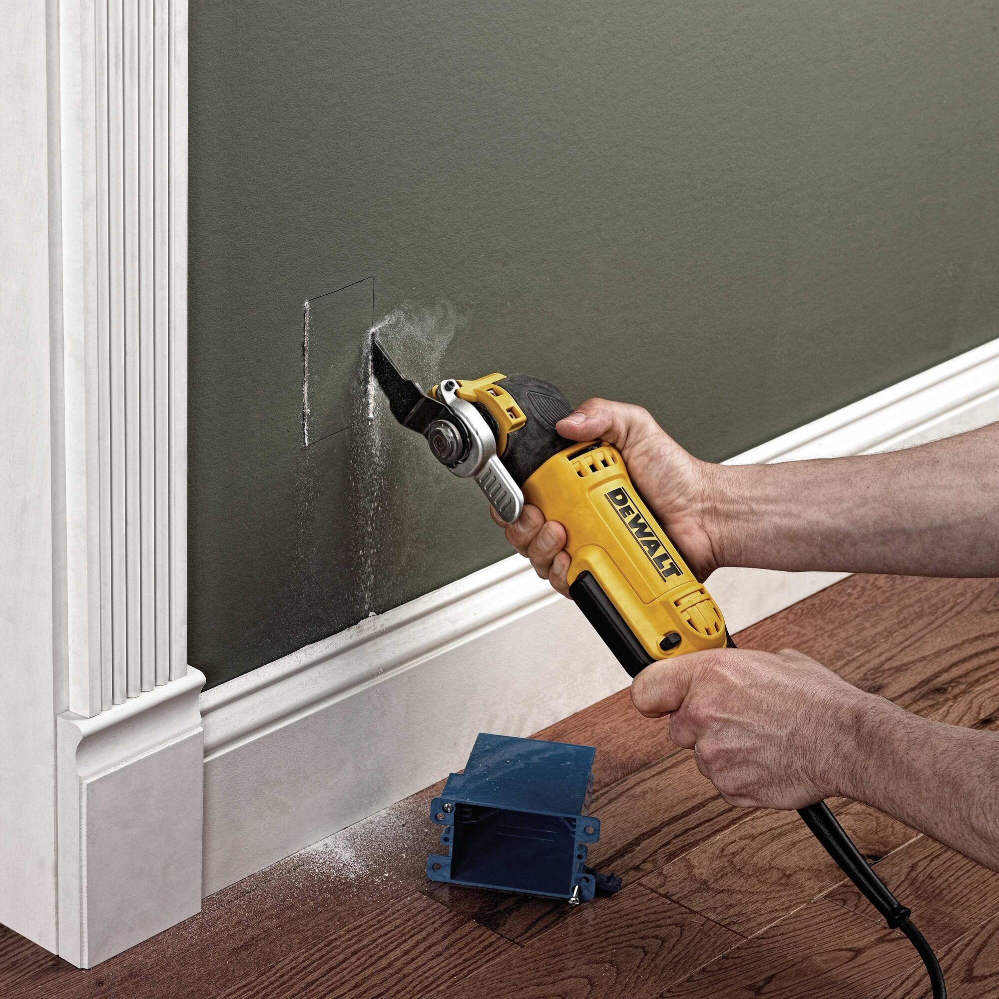 Oscillating multi tool kit being used to cut into wall.