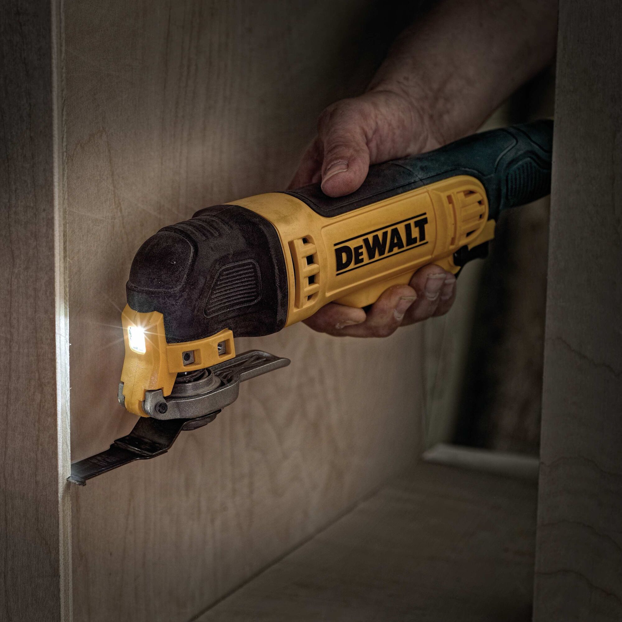 Oscillating multi tool kit being used to cut wood.