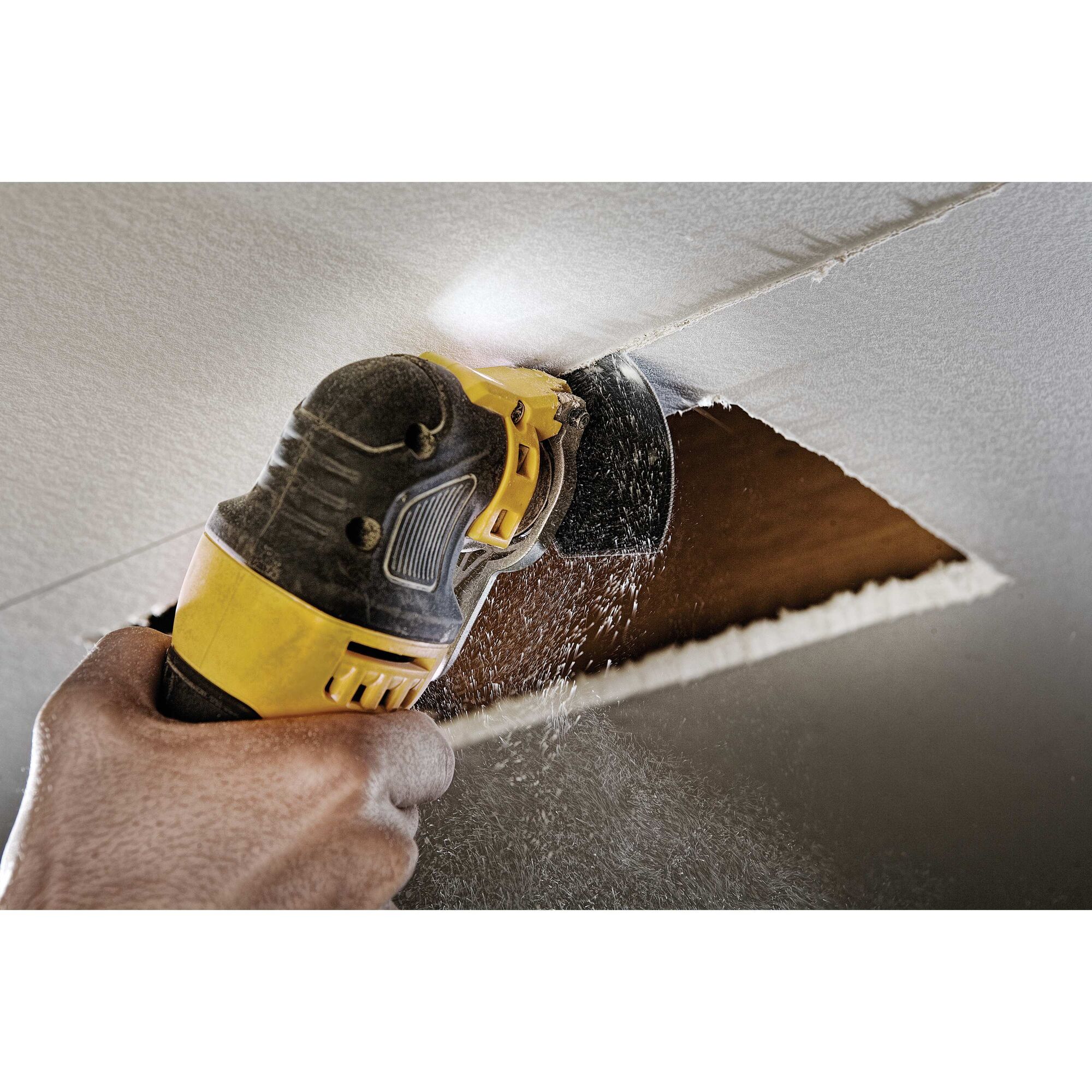 Oscillating multi tool kit being used to cut into ceiling.