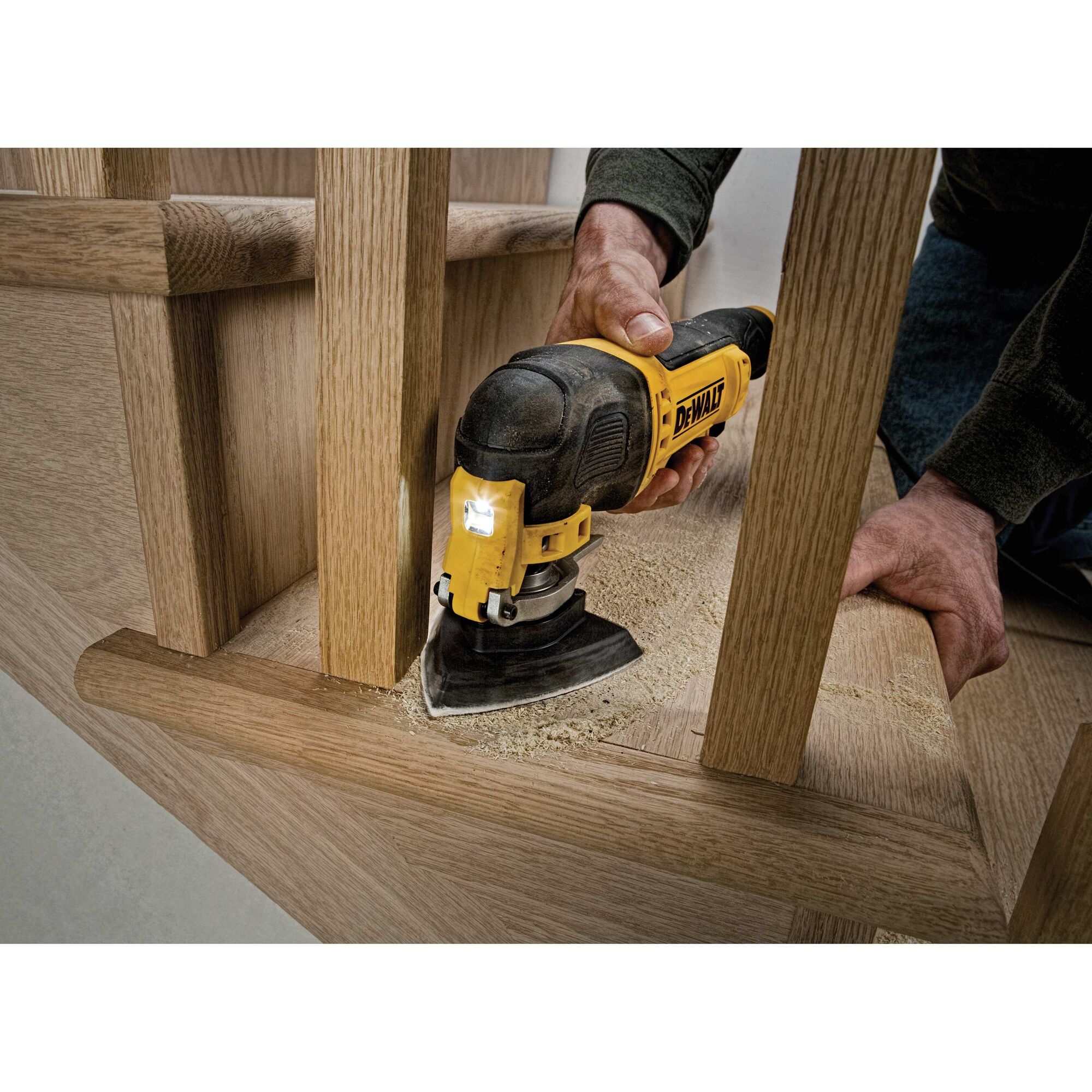 Oscillating multi tool kit being used to sand wood.
